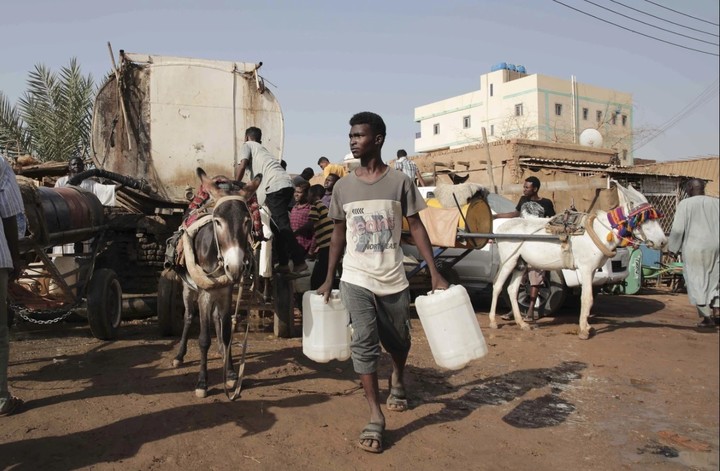 Sudaneses se dirigen a cargar agua, en Jartum. Foto:  AP/ archivo
